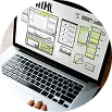 Desk with a laptop showing wireframes and web maintenance notes.