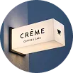 Cream-colored projecting sign reading 'Crème Coffee & Cake'.