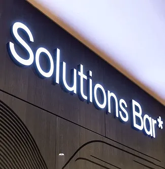 Illuminated 'Solutions Bar' sign on a dark wood wall.