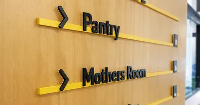 Interior directional signage with black lettering and arrows on a wood wall.
