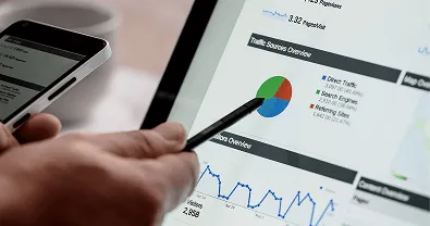 Person pointing at an analytics dashboard on a laptop with charts and reports.